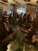 Glass cabinet display of multiple hand carved gnome figurines and small vintage bicycle sculpture.