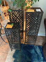 Three black metal plant stands with woven lattice design, different sizes shown together on floor, no plants on stands