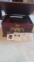 Full front-angle view of the Art and Sound entertainment center with open turntable lid and instruction sheet