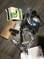 H2O SteamFX steamer components shown including main handheld unit, attachments wrapped in plastic, and folded instruction manual.