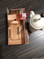 Photo of the La Cafetière drinking chocolate maker outside its box showing the pot with plunger resting beside the box.