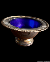 Side angle showing silver plated ornate edging, cobalt blue glass interior and pedestal base with some tarnish.