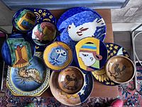 Top view of the entire set showing all bowls and plates with various colorful Mexican folk art designs.