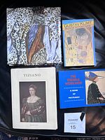 Top view showing assortment of postcard books and loose postcards arranged on a black surface, featuring Gustav Klimt, Tiziano, and Vienna Workshop books.