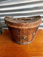 Front view of vintage leather hat box showing patina, strap, and lock mechanism.