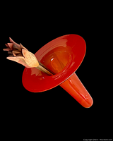 Red glass vase lying on its side with three wooden tulip flowers inside, set against a black background.