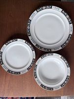 Top view of 2 dinner plates, 1 appetizer plate, 1 soup bowl showing floral rim pattern and white ceramic centers