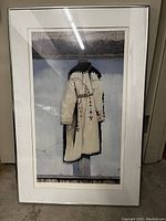 Full view of framed print showing traditional coat image with frame and glass reflections.