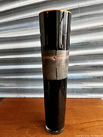 Front view of tall black glass cylinder vase on wooden surface
