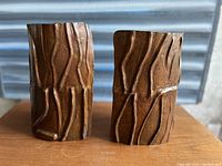 Pair of bronze bookends shown together on wooden surface with metal background.