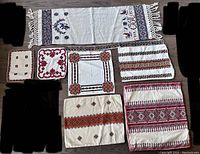 Top-down photo showing seven different pieces of embroidered Ukrainian textiles arranged flat, featuring various traditional embroidery patterns.