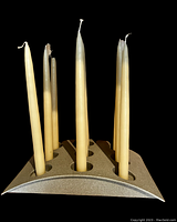 Front angle of the black metal candle holder displaying 9 cream taper candles inserted in circular holders.