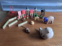 Full view of the collection showing ceramic animals, wooden miniature buildings, fence pieces, green trees, and black metal animals