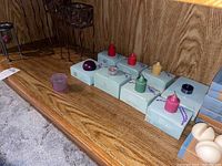 Overview of boxed PartyLite candles in various colors including pink, red, orange, green, and dark purple along with a purple glass tealight holder