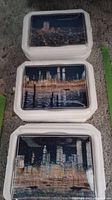 Stack of three rectangular plates depicting the Twin Towers in night views on a grey carpet background.