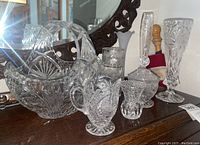 Large handled basket-style vase, tall narrow vases, candy dish with lid, creamer, canisters in arrangement on dresser