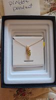 10kt gold necklace with peridot pendant displayed on white necklace holder inside a black box.