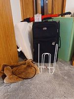 Full shot showing black suitcase, brown faux fur bag, white fluff ball remover, and medical wedges in background and red umbrella on top of suitcase.