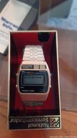 Front view of Quastran Quartz digital watch inside original box showing face and metal band.