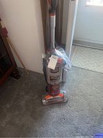 Shark upright vacuum cleaner in gray with orange accents, showing front angle with dust canister, handle and power nozzle.