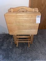 Front view of four wooden TV trays folded and placed in the wooden rack.
