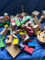 Photo showing Fisher Price Cookie Pig toy, wooden blocks, and bead maze puzzle toy arranged together on a blue background.