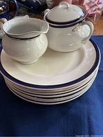 Set of 8 plates stacked, with cream pitcher and gravy boat on top, showing design and size