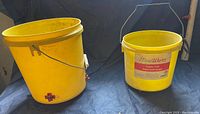 Photo of two yellow plastic buckets with handles, one larger with a red cross and one smaller labeled HomeWyse.