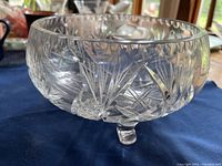Close-up photo showing clear cut crystal terrine with etched floral and starburst patterns and a tiny chip on the rim.