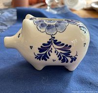 Side view of blue and white handpainted Delft porcelain piggy bank showing floral patterns on the side including the pig's snout and ears.