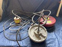 Photo showing two floating and submersible water heaters with cables and protective cages on a blue tarp.