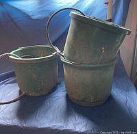 Front view of three green stock buckets; two with attached black heated power cords, one bucket without cord.