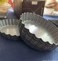 Close-up photo showing stacked round mini quiche nonstick baking tins with scalloped edges