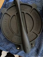 Top view of cast iron tortilla press showing embossed text and handle