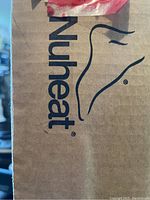 Close-up photo of the cardboard box with Nu Heat branding visible, indicating product brand and authenticity.