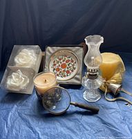 Photo of the Lenox pewter candle holder, two rose candles, vanilla candle in decorative glass, ornate floral small dish with gold rim, mini glass oil lamp with brass base, brass candle snuffer
