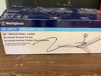 Box showing Westinghouse brand, 56 inch industrial look ceiling fan with brushed nickel finish and steel blades.