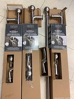 Three boxed curtain rod sets each containing adjustable metal rods, spherical finials, and mounting hardware.
