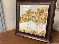 Front view of framed ceramic tile artwork showing birch trees with autumn foliage colors and artist signature.