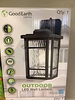 Front side of box showing product name Good Earth Outdoor LED Wall Lantern and features including dusk to dawn, LED bulb included, wet location rated, 800 lumens brightness, 120V direct wire.