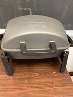 Closed view of the Nexgrill portable grill showing lid, handle, and sturdy legs.