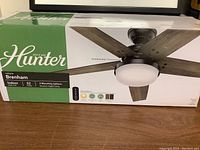 Front of sealed Hunter Brenham ceiling fan box showing assembled fan image and brand logo