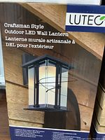 Front package photo showing a single wall lantern mounted outdoors, emphasizing craftsman style and LED lighting.