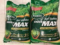 Photo showing two unopened green bags of Scotts Turf Builder Green Max lawn food with visible branding and product information.