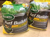 Two large bags of Scotts Turf Builder Weed & Feed lawn food showing front packaging with product name, fertilizer ratio, and branding.
