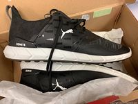 Pair of black Puma Ignite NXT shoes inside a box with white midsole and black upper featuring Puma branding.