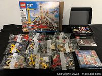 Two LEGO City sets visible with fire truck box and numerous unopened numbered bags containing LEGO bricks and accessories, instructions visible.