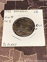 Photo of one side of the 1792 Barbados half penny coin in a white cardboard holder labelled with date, origin, and denomination.