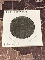 Obverse side of the 1889 Guernsey 8 Doubles coin showing denomination and year with wreath design.