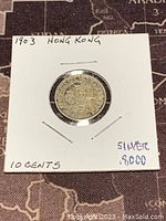 Reverse side of 1903 Hong Kong silver 10 cents coin showing denomination and date in a white paper holder.